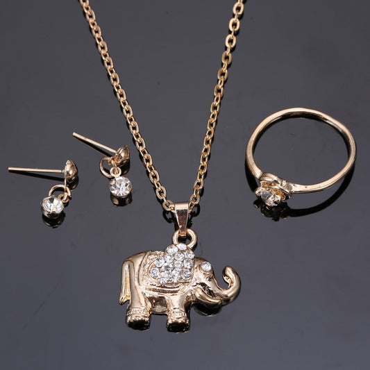 Rose gold-toned jewelry set with an elephant pendant necklace, matching rhinestone drop earrings, and a heart-knot ring.