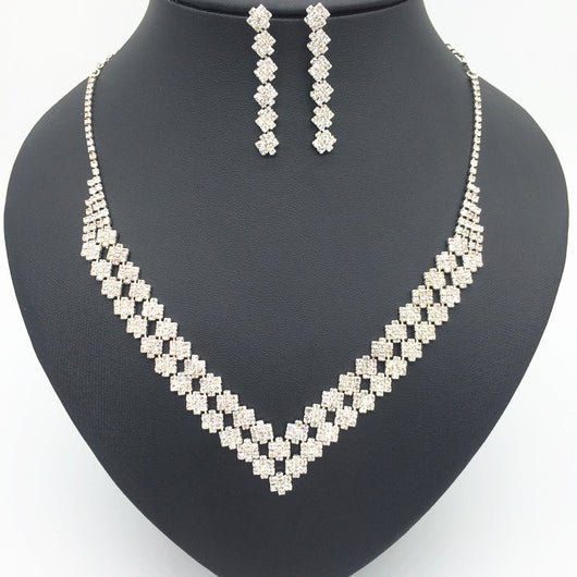 Sparkling silver-tone rhinestone necklace and matching dangle earrings set, featuring a V-shaped design on a black bust.