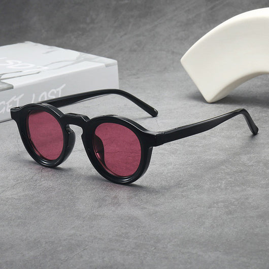 Vintage round frame sunglasses with black frames and pink lenses on a gray surface. - Image 10