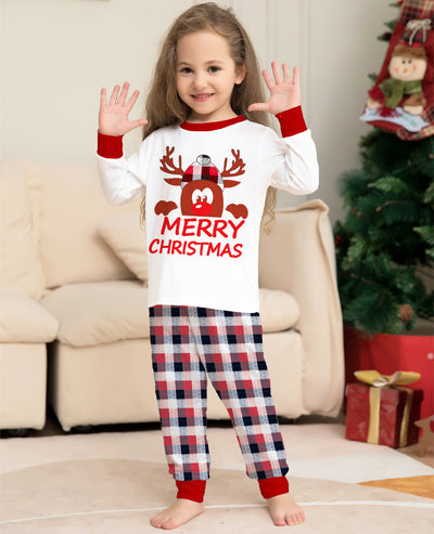 Young girl in a white long-sleeve Christmas pajama top with a reindeer graphic and red plaid pajama pants. - Image 4