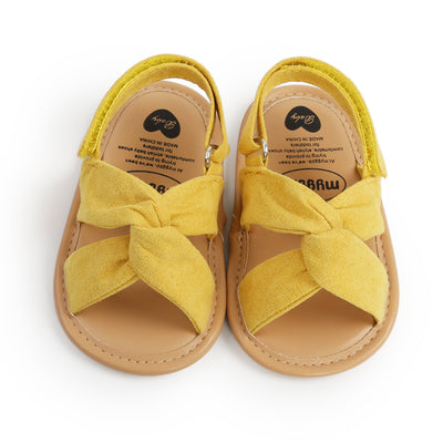 Black baby sandals with knotted cross straps and a matching black floral headband on a white background. - Image 6