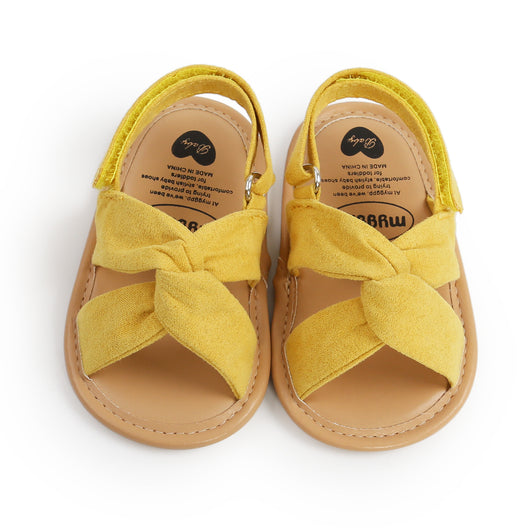 Black baby sandals with knotted cross straps and a matching black floral headband on a white background. - Image 6