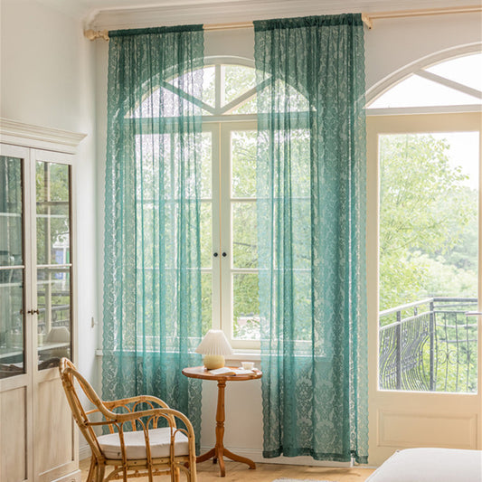 Close-up of a dark green lace curtain with an intricate floral and scrollwork pattern on sheer polyester fabric.