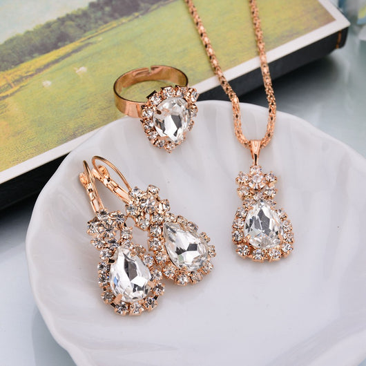 Rose gold-toned necklace, earrings, and ring set with large oval clear gemstones surrounded by smaller stones. - Image 30