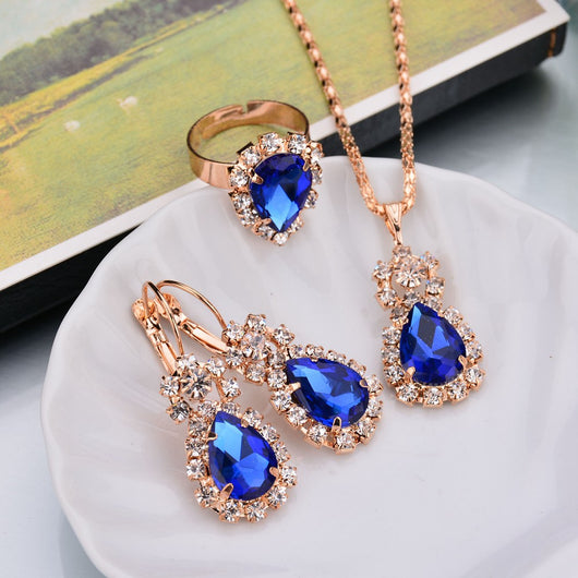 Rose gold-toned necklace, earrings, and ring set with large oval clear gemstones surrounded by smaller stones. - Image 3