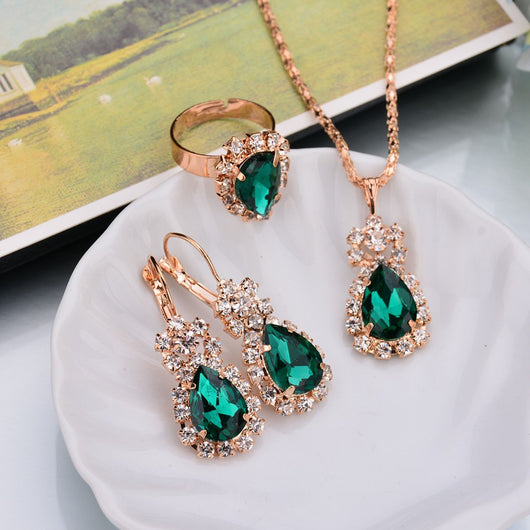 Rose gold-toned necklace, earrings, and ring set with large oval clear gemstones surrounded by smaller stones. - Image 11