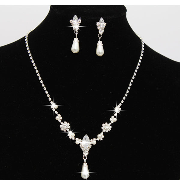 Purple rhinestone and faux pearl necklace and drop earrings set on a black display. Features silver-tone settings.