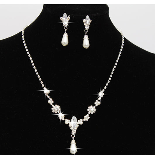 Purple rhinestone and faux pearl necklace and drop earrings set on a black display. Features silver-tone settings.
