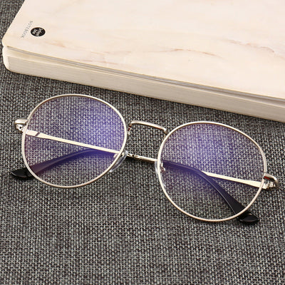 Black round anti-blue light glasses with clear lenses showing a blue reflection, resting on a gray textured surface. - Image 5