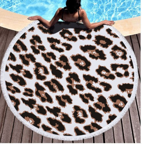 Round white microfiber beach towel with a vibrant blue and purple feather print and white fringe trim.