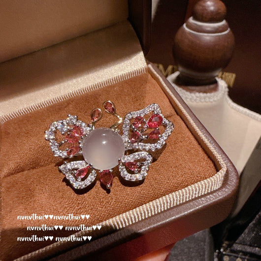 Pair of sparkling rose-shaped stud earrings, encrusted with clear gemstones, displayed in a brown jewelry box.