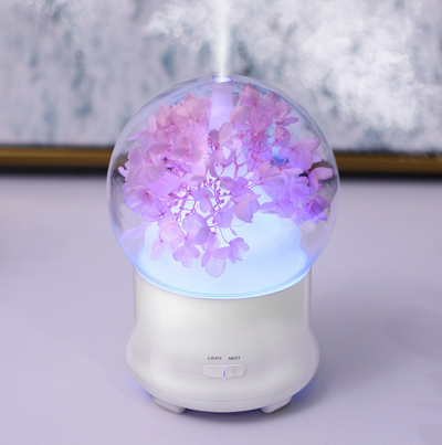 White aromatherapy machine with a clear dome top, featuring blue preserved flowers and an aqua glow. Includes 'LIGHT' and 'MIST' controls. - Image 10