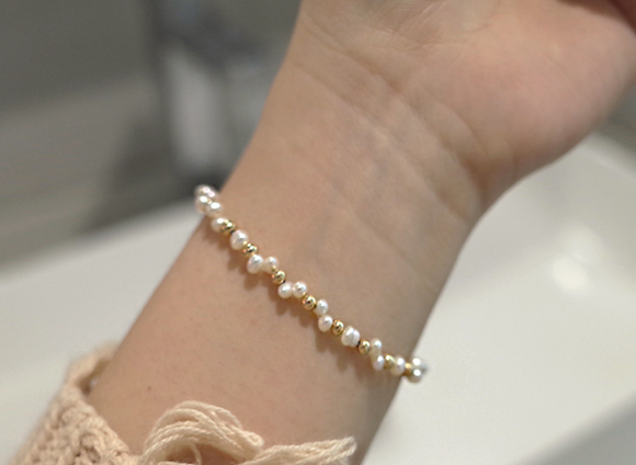 Pulsera Dorada con Bolsita Tejida de Perlas Naturales y Diseño Estelar