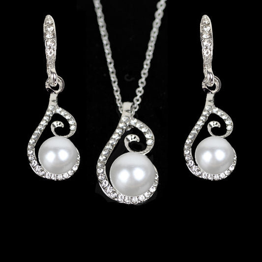 Silver-tone rhinestone and faux pearl drop necklace and matching earrings jewelry set on a black background.