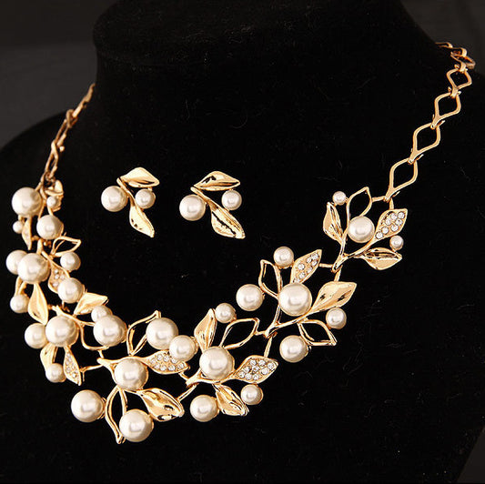 Gold-toned necklace and matching earrings set with faux pearls and clear rhinestones in an elegant leaf and vine design.