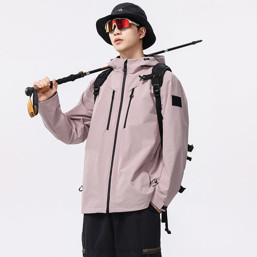 Man wearing a black windproof and waterproof outdoor jacket with a hood, sports sunglasses, and a bucket hat, holding a trekking pole.