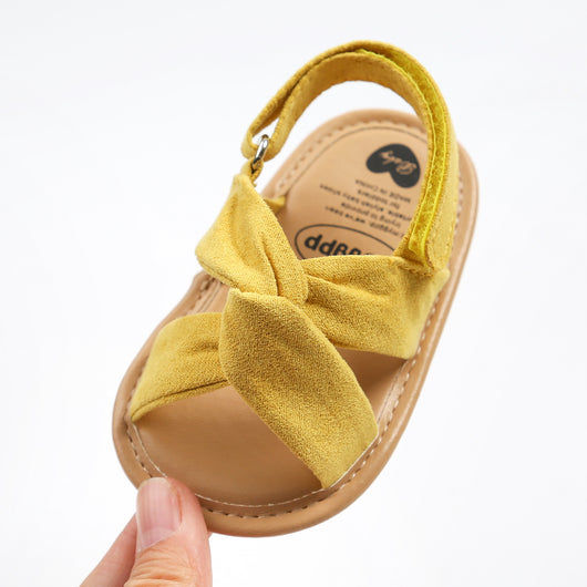Black baby sandals with knotted cross straps and a matching black floral headband on a white background. - Image 30