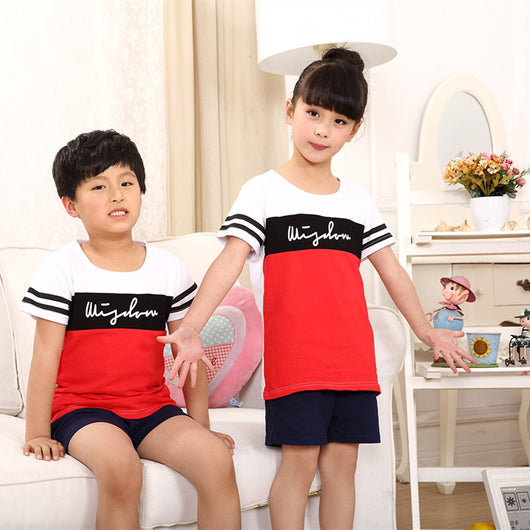 Family of four wearing matching black, white, and red color block t-shirts with navy shorts, posing happily. - Image 3