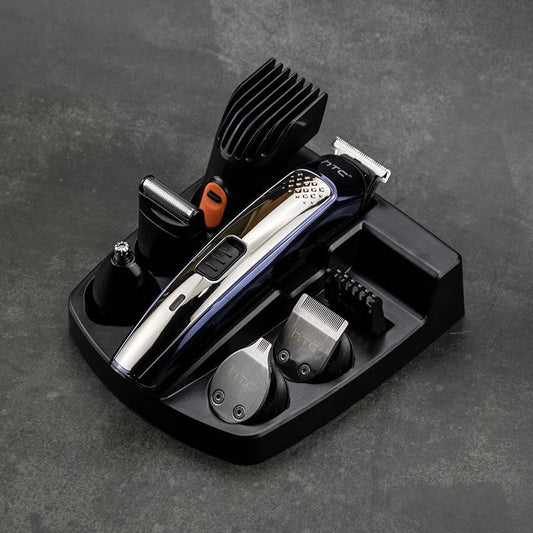 Five-in-one HTC electric hair clipper set with multiple attachments and a black charging stand on a dark background.