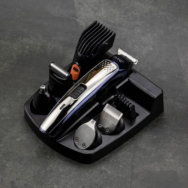 Five-in-one HTC electric hair clipper set with multiple attachments and a black charging stand on a dark background.