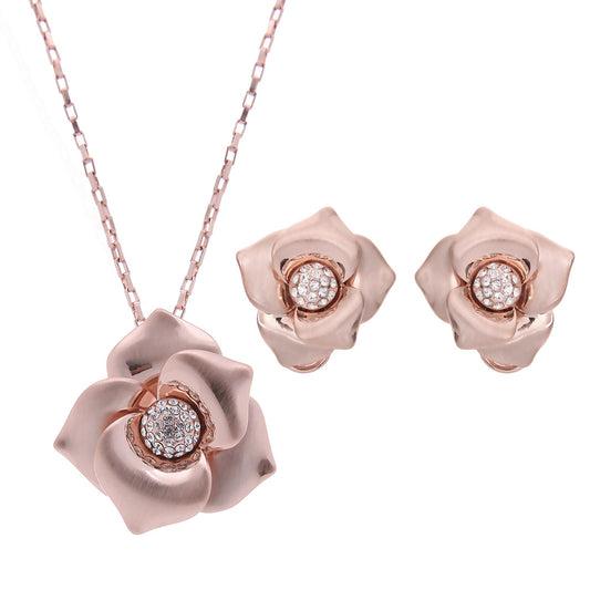 Rose gold-toned necklace and stud earrings set with floral design and clear rhinestone accents.