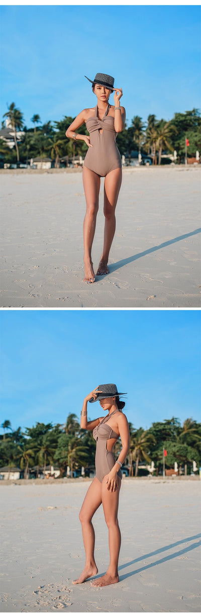 Woman wearing a taupe ribbed one-piece swimsuit with a halter neckline and twisted bust detail on a sandy beach. - Image 15