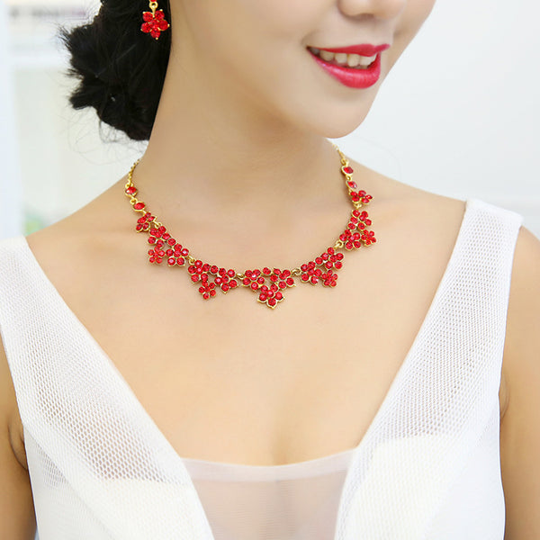 Sparkling crystal bridal jewelry set with floral necklace, drop earrings, and a matching tiara on a bride.