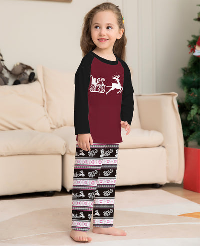Child wearing a Christmas pajama set with a maroon and black reindeer top and black, pink, and white striped pants. - Image 6