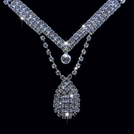 Sparkling silver-toned bridal necklace and matching drop earrings set with clear rhinestones. The necklace features a V-shape and a teardrop pendant, while the - Image 4