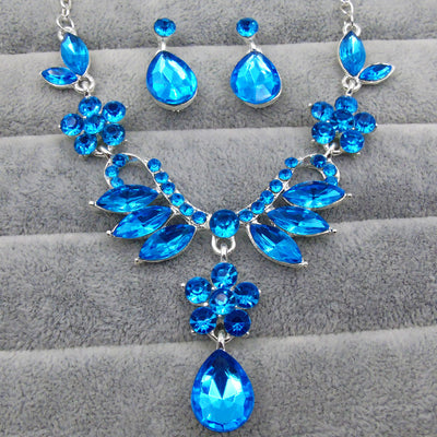 Purple rhinestone statement necklace with silver-tone setting, featuring floral and leaf motifs and a teardrop pendant.