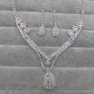 Sparkling silver-toned bridal necklace and matching drop earrings set with clear rhinestones. The necklace features a V-shape and a teardrop pendant, while the - Image 2