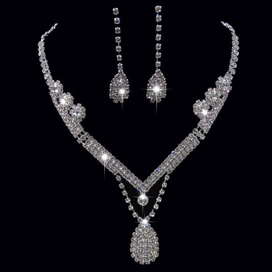 Sparkling silver-toned bridal necklace and matching drop earrings set with clear rhinestones. The necklace features a V-shape and a teardrop pendant, while the