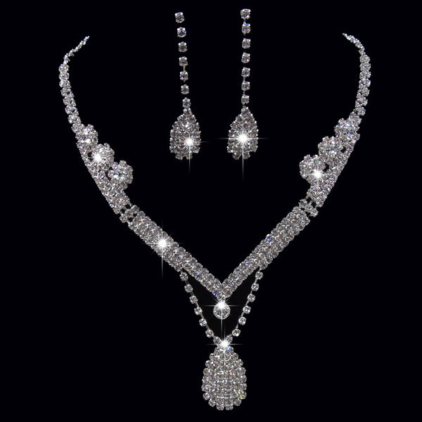 Sparkling silver-toned bridal necklace and matching drop earrings set with clear rhinestones. The necklace features a V-shape and a teardrop pendant, while the