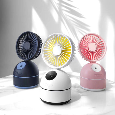 Dark grey fan humidifier with a round fan head and spherical base, emitting mist, on a white desk.