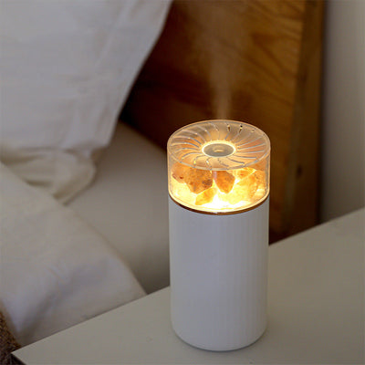 White portable aromatherapy humidifier with a clear top section displaying glowing pink salt crystals and a silver band.