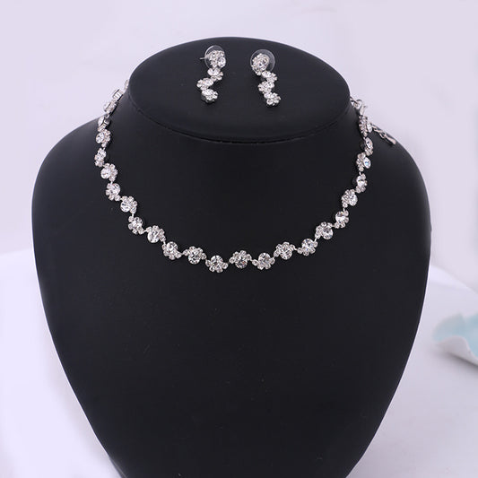 Sparkling silver-tone necklace and stud earrings set with clear round rhinestones, displayed on a black jewelry bust.