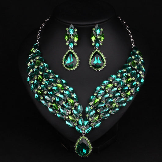 Green and teal rhinestone necklace and matching dangle earrings set on a black jewelry stand. - Image 4
