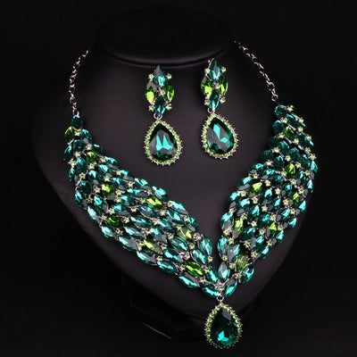 Green and teal rhinestone necklace and matching dangle earrings set on a black jewelry stand. - Image 5