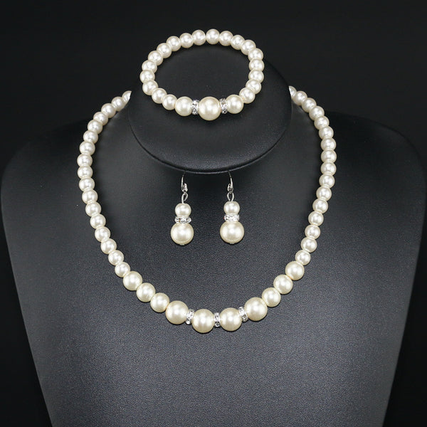 Three-piece cream faux pearl jewelry set with rhinestone accents, including a necklace, bracelet, and drop earrings.