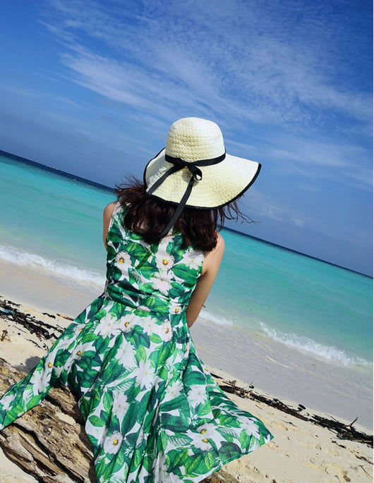 Boy in white t-shirt and floral shorts holding hands with girl in matching floral dress on a sunny beach. - Image 3