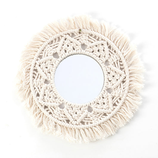 Circular mirror with a beige macrame fringe border, featuring intricate knotwork around the reflective surface.