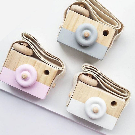 Two-tone wooden toy camera in natural wood and light blue with a cream fabric strap, for babies and kids.