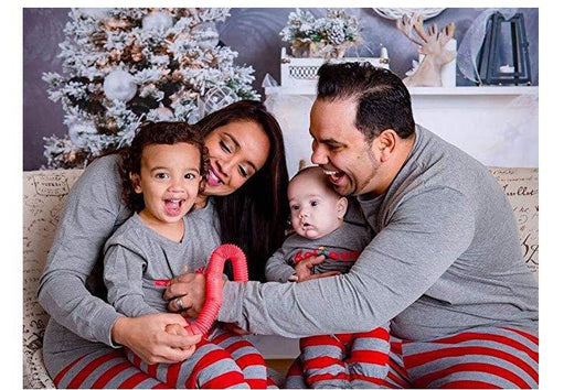 Family of four in matching grey long-sleeve tops and red striped pants, posing in a festive holiday setting.