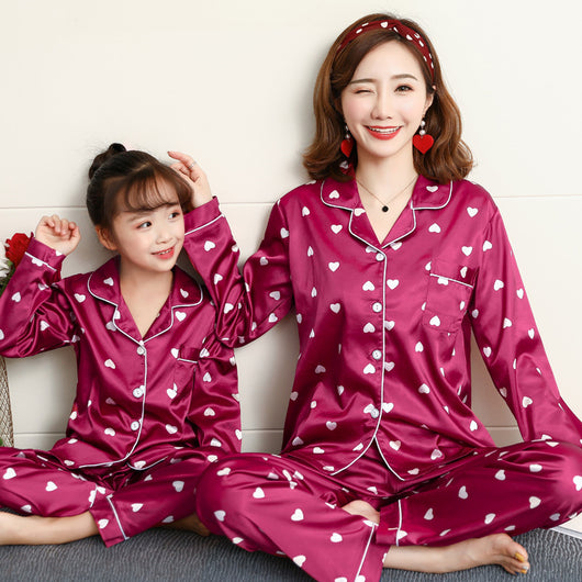 Mother and daughter in matching light blue satin pajamas with pink cherry print, sitting on a gray sofa. - Image 5