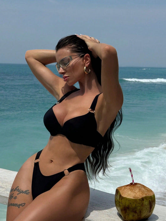 Woman in a black pure color bikini with gold O-rings, featuring a push-up top and high-cut bottoms, by the ocean. - Image 7