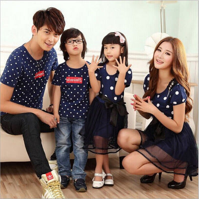 Family of four wearing matching white and black polka dot outfits. Dad and son in t-shirts, mom and daughter in dresses.