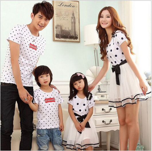 Family of four wearing matching white and black polka dot outfits. Dad and son in t-shirts, mom and daughter in dresses. - Image 13