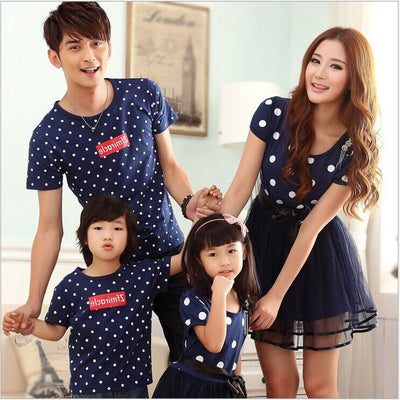 Family of four wearing matching white and black polka dot outfits. Dad and son in t-shirts, mom and daughter in dresses. - Image 3