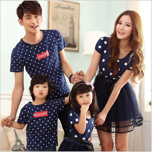 Family of four wearing matching white and black polka dot outfits. Dad and son in t-shirts, mom and daughter in dresses. - Image 3
