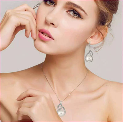 Silver-tone rhinestone and faux pearl drop necklace and matching earrings jewelry set on a black background. - Image 7